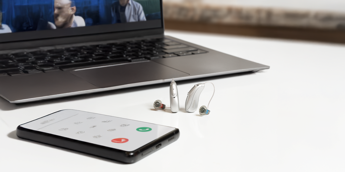 Dva Phonak slušna aparata povezana sa aplikacijom pored laptopa