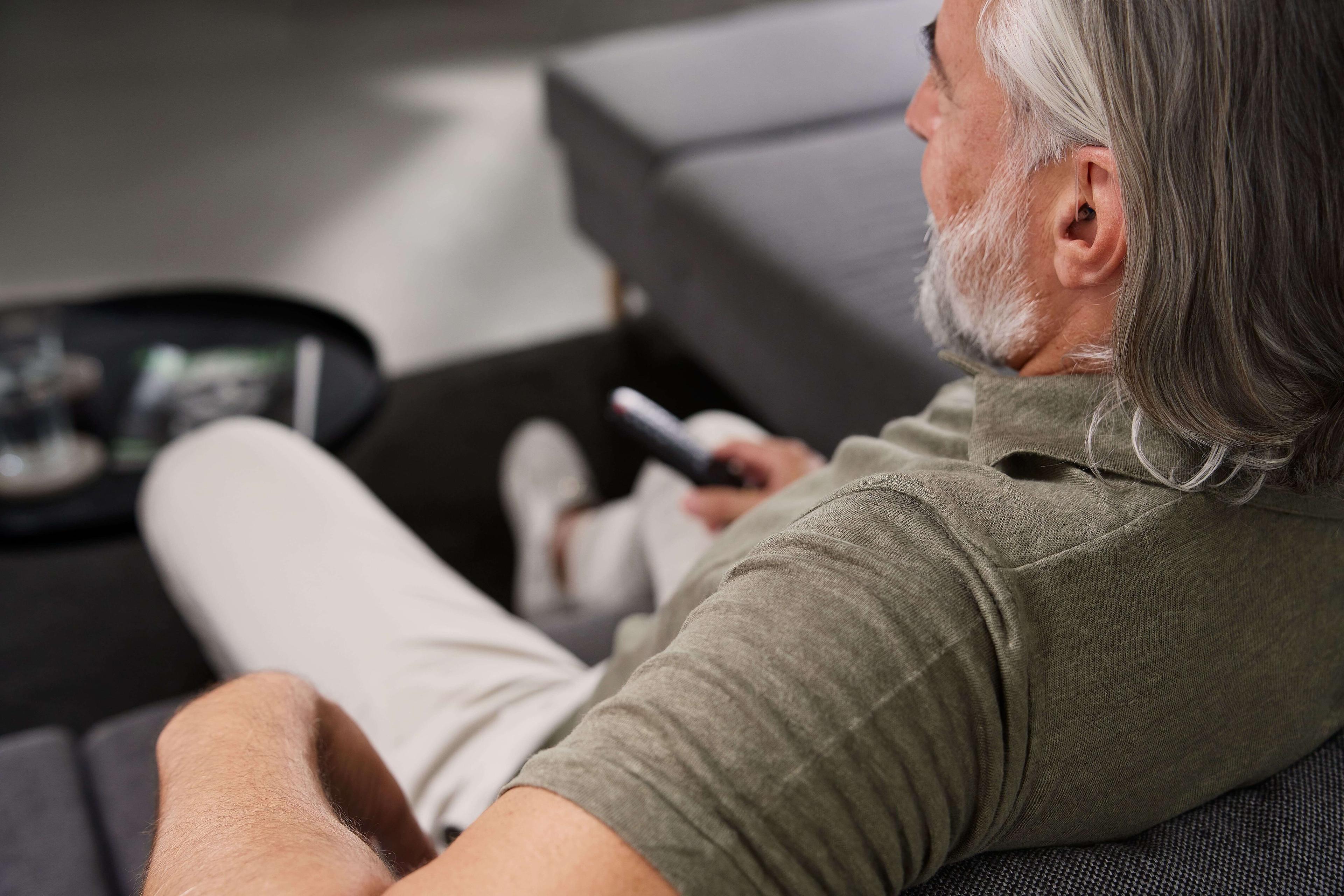 Mann auf Couch von hinten beim Fernsehen 