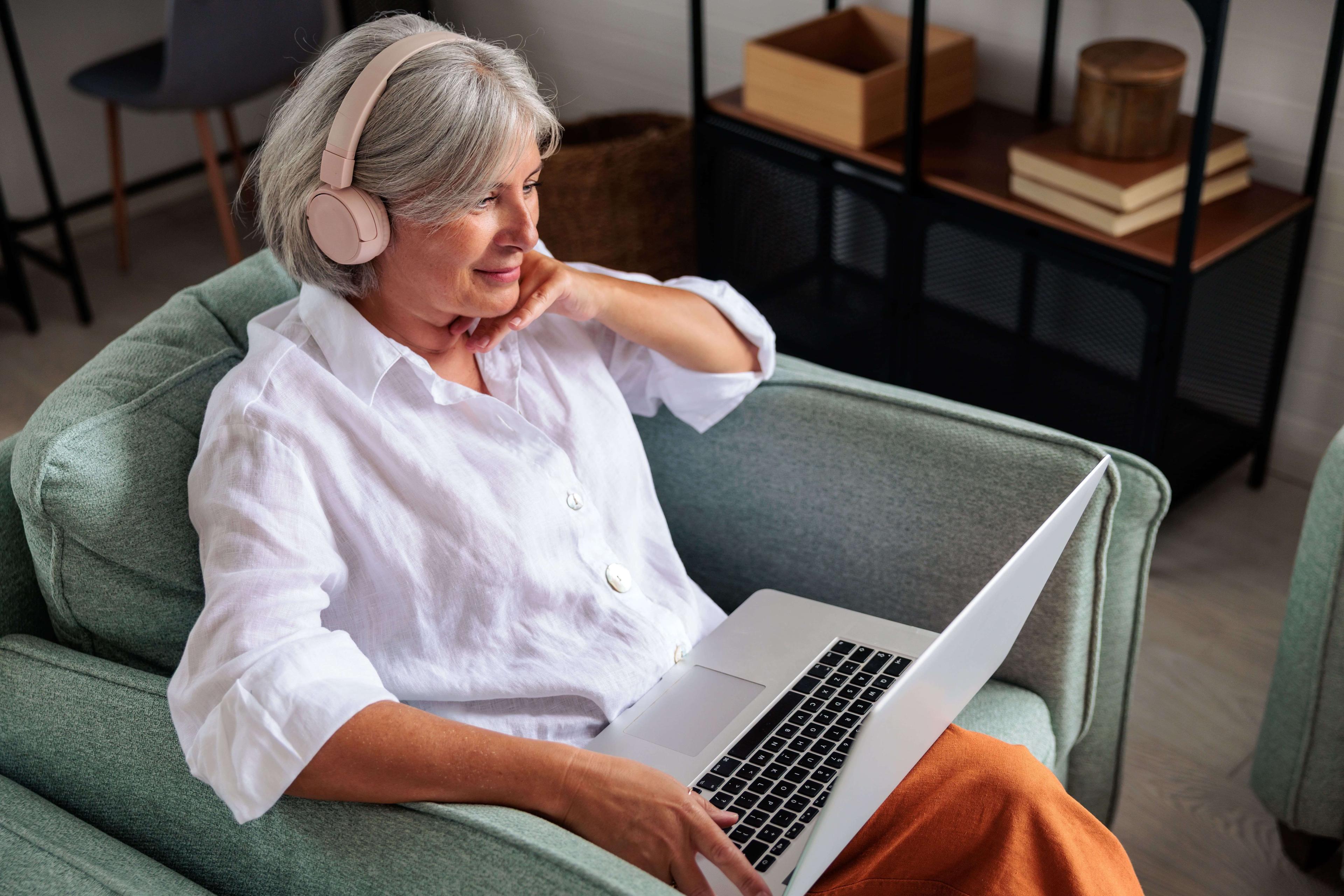 Frau daheim mit Laptop auf der Couch bei Online Hörtest