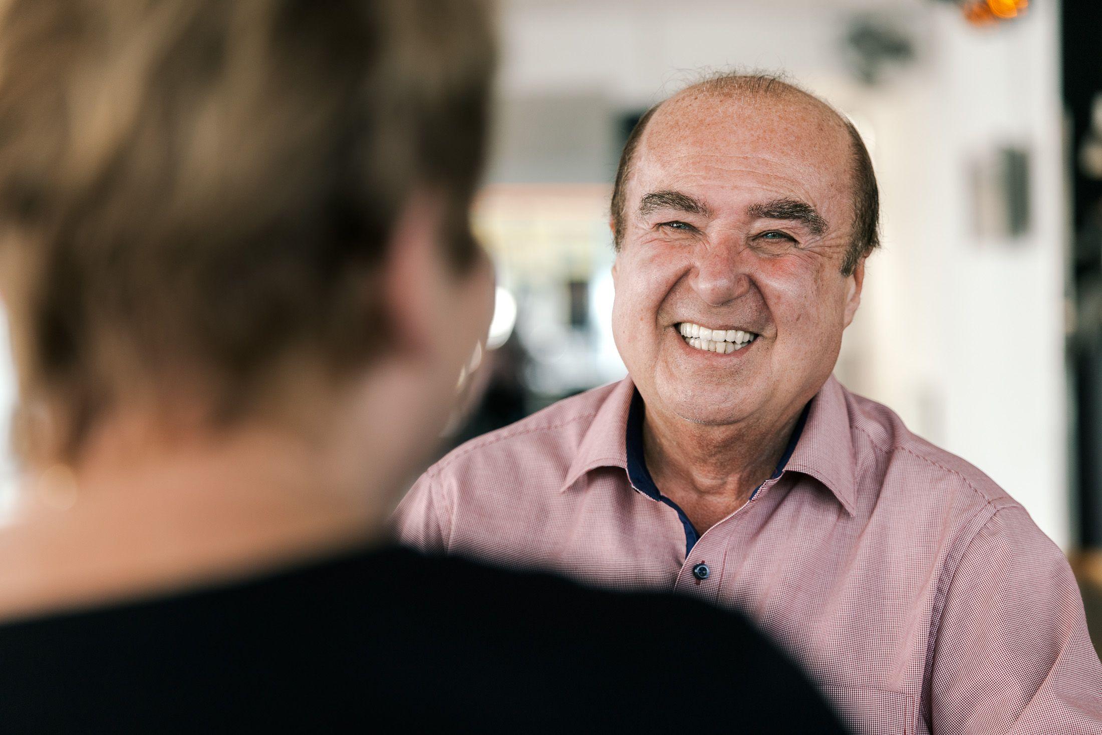 Johannes Besau im Gespräch mit seiner Tanzpartnerin, lächelnd. In rosa Hemd.