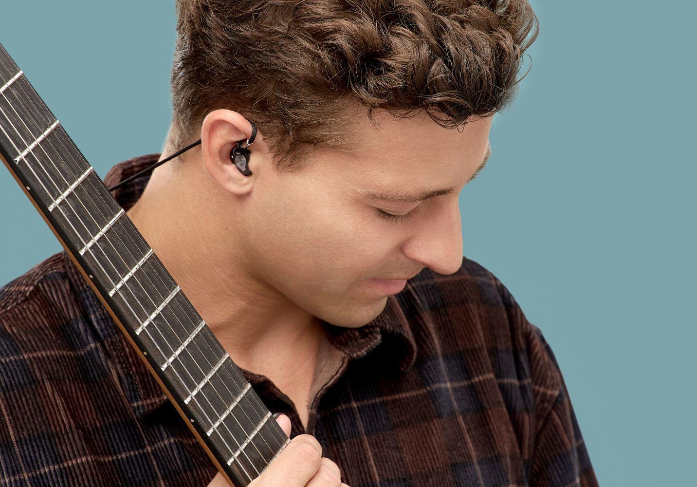 Mann mit Gehörschutz und Gitarre