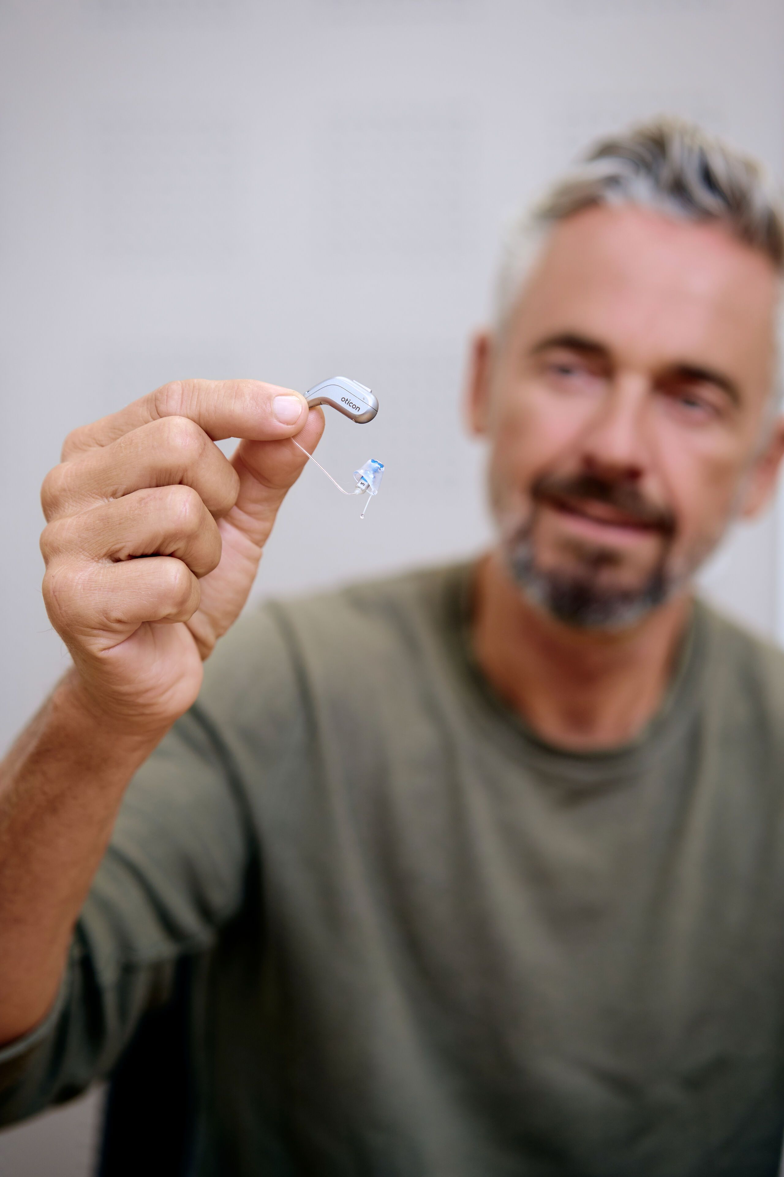 Mann mit Hinter-dem-Ohr-Hörgerät in der Hand