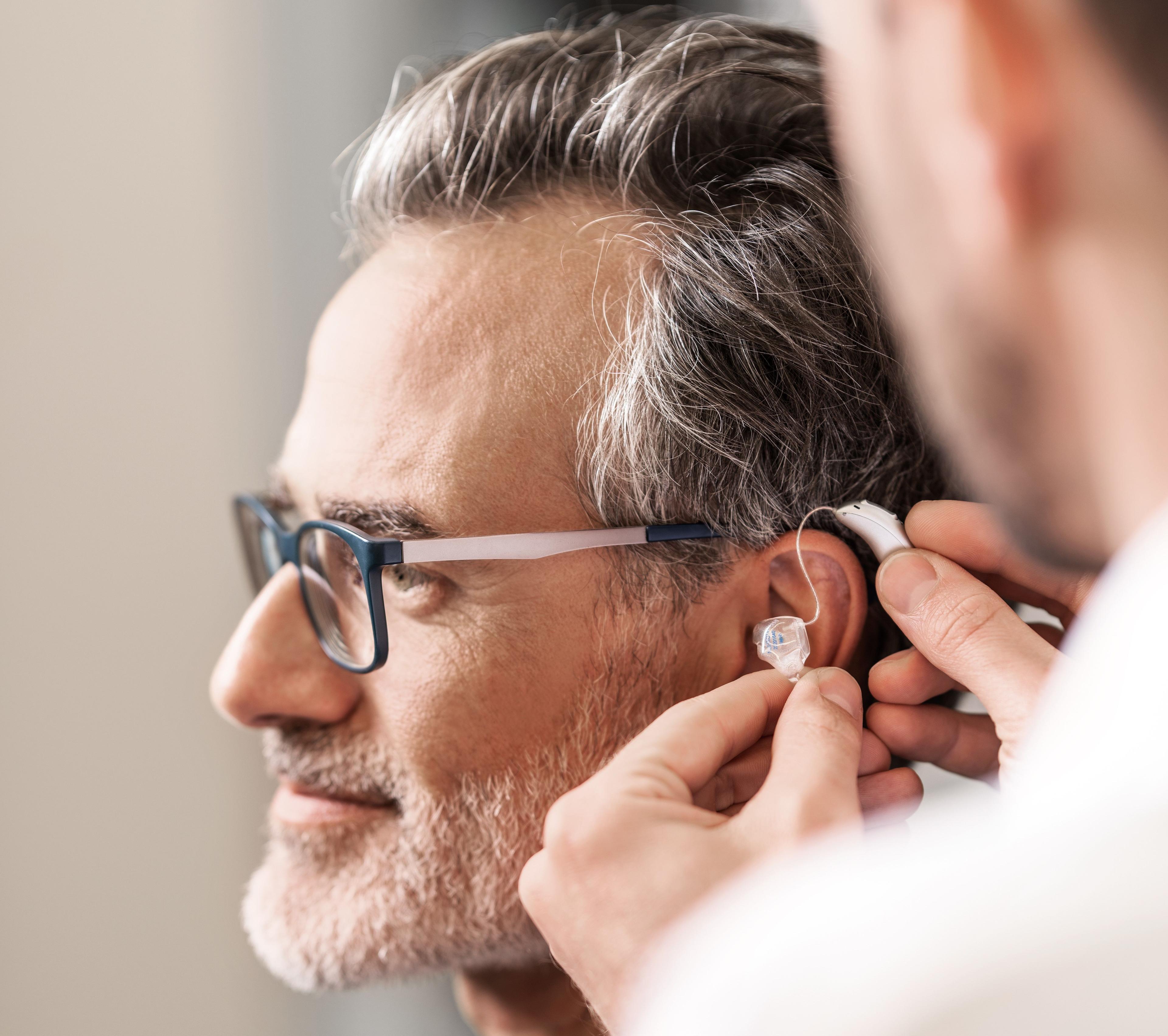 Mann mit Hörgerät und Brille
