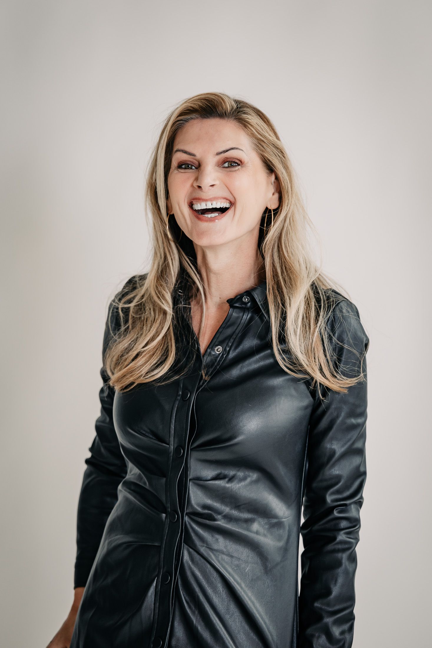 Halbkörper Bild von Martina Kaiser beim Fotoshooting in Lederkleid, lachend. 