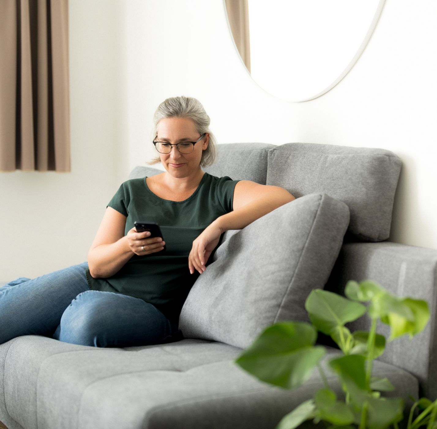 Neuroth Mitarbeiterin sitzt auf Couch mit Handy