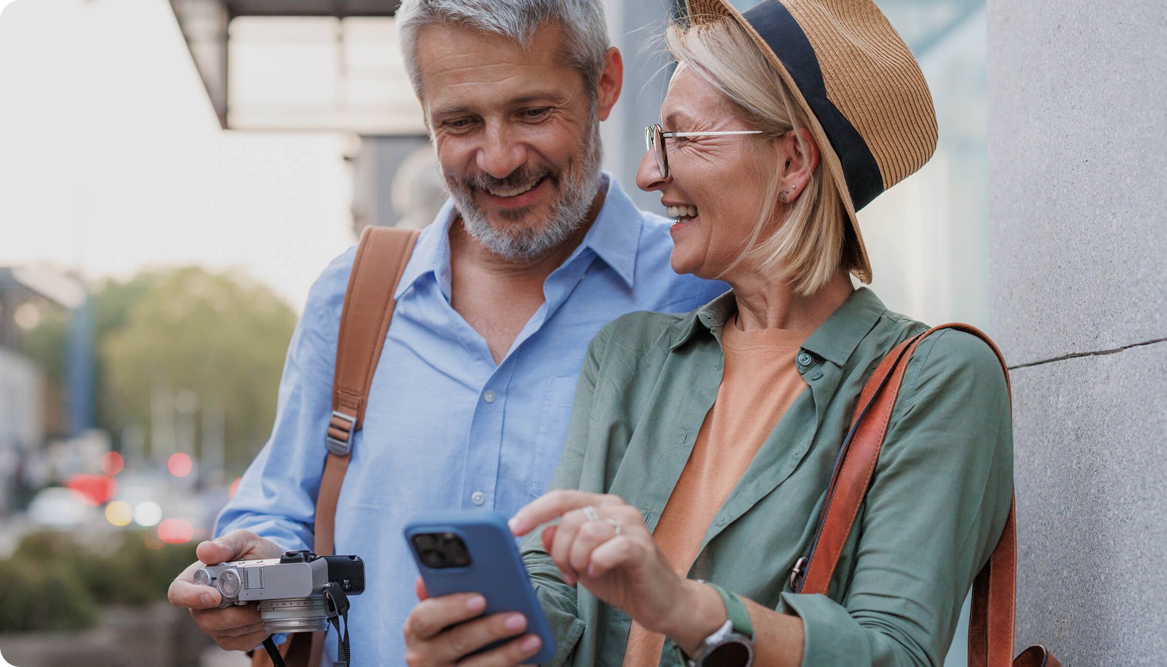 Pärchen kommt im Urlaub am Bahnhof an und schaut aufs Smartphone