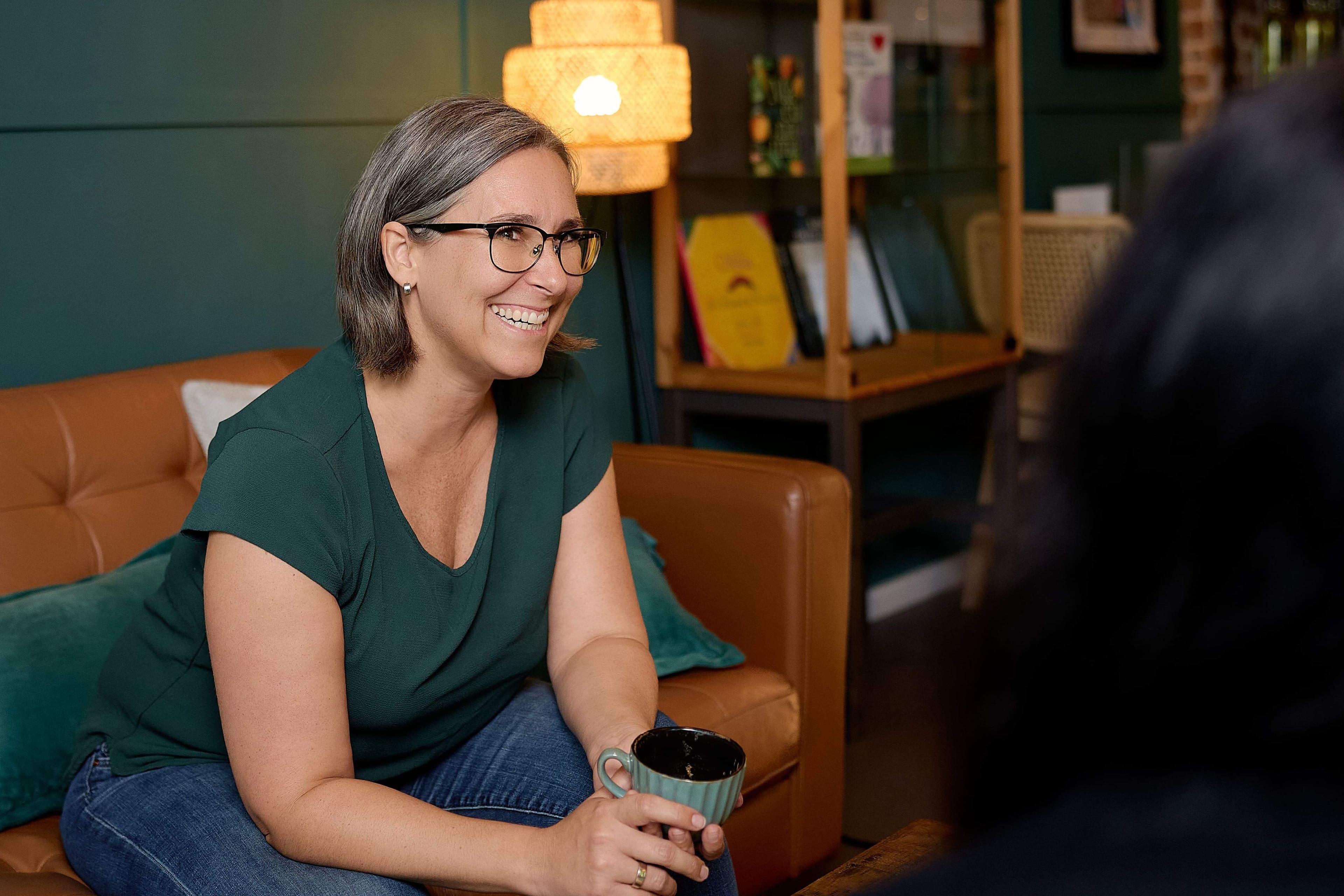 Frau in Cafe mit Kaffee lachend 