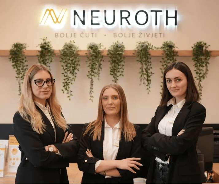Tri mlade Neuroth akustičarke stoje skrštenih ruku u prostorijama Neurotha, sa logom kompanije iznad njih