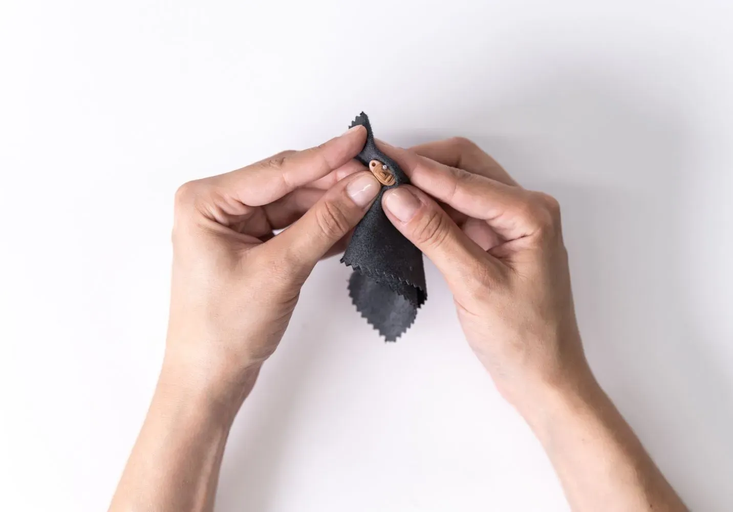 Roke, ki čistijo slušni aparat s sivo krpico. 