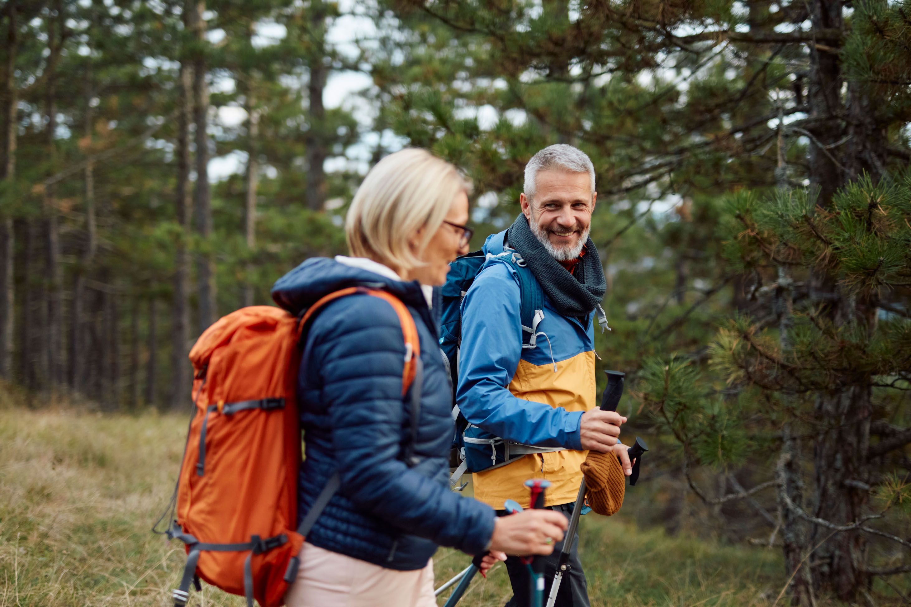 Couple riant en randonnee avec sacs a dos dans la foret