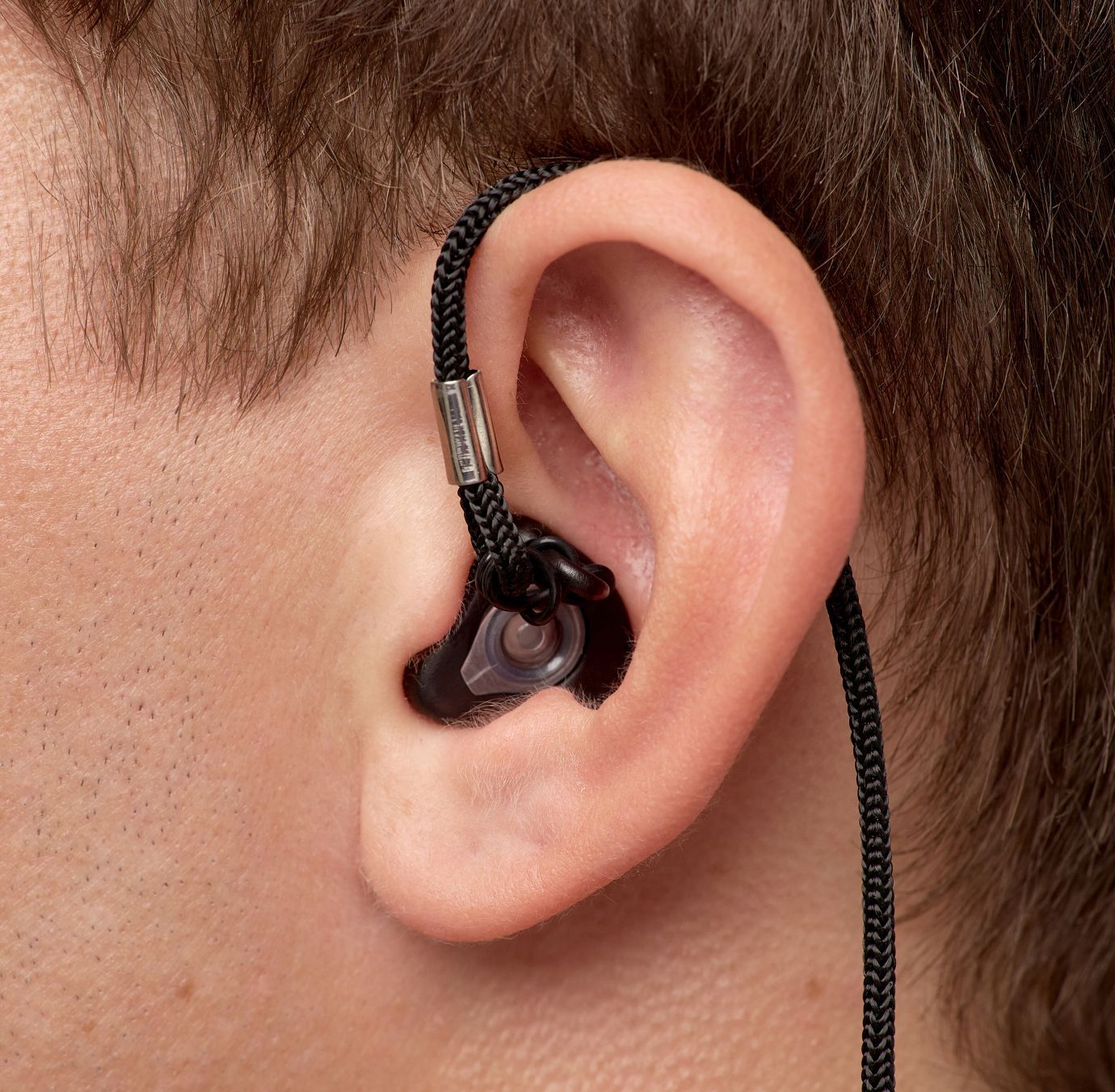 Detaljni prikaz Earwear zaštite u uhu crne boje sa kanapom u uhu muškarca 