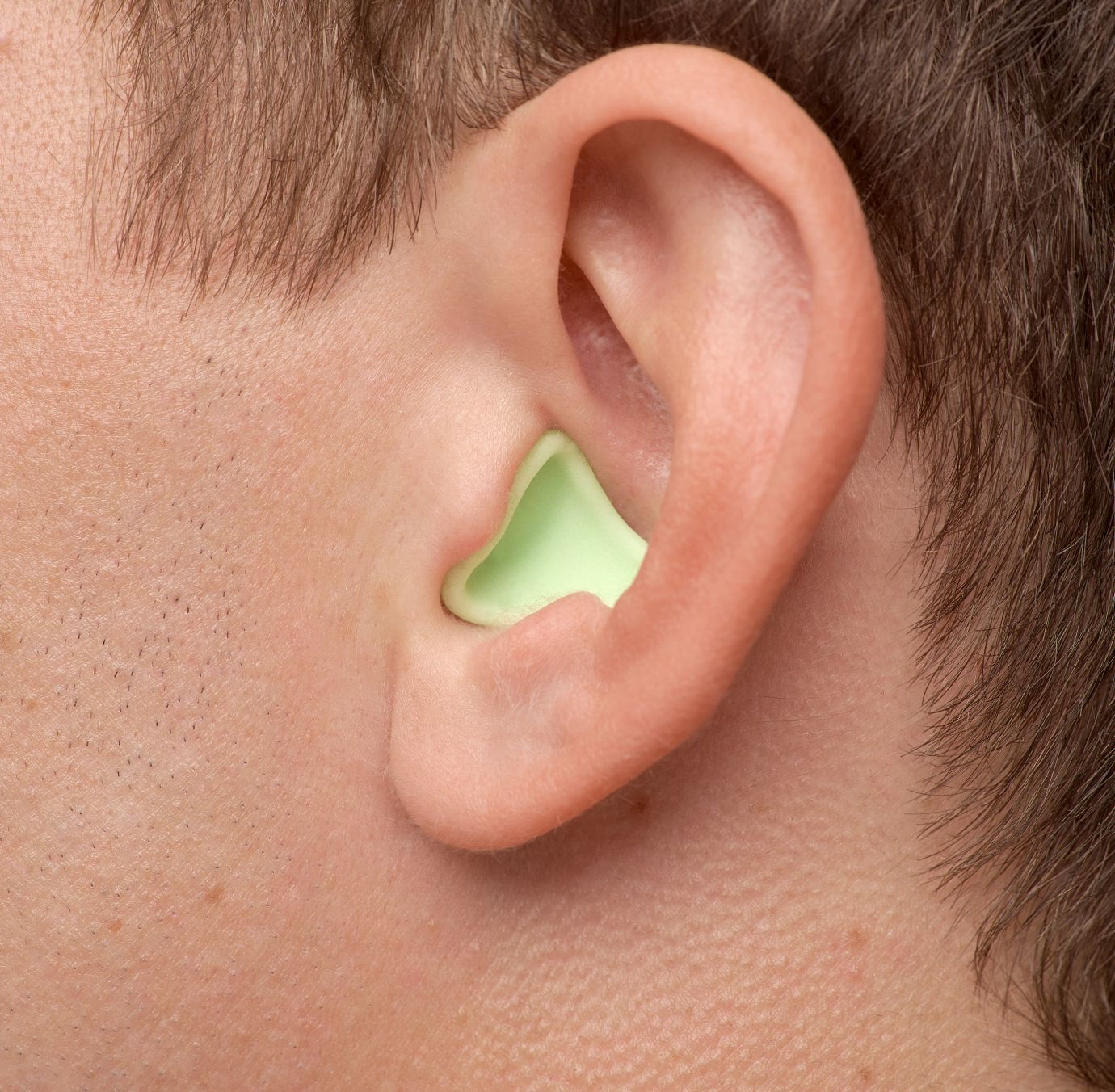 Detaljan prikaz Earwear Sleeo zaštite za sluh u zelenoj boji u uhu muškarca