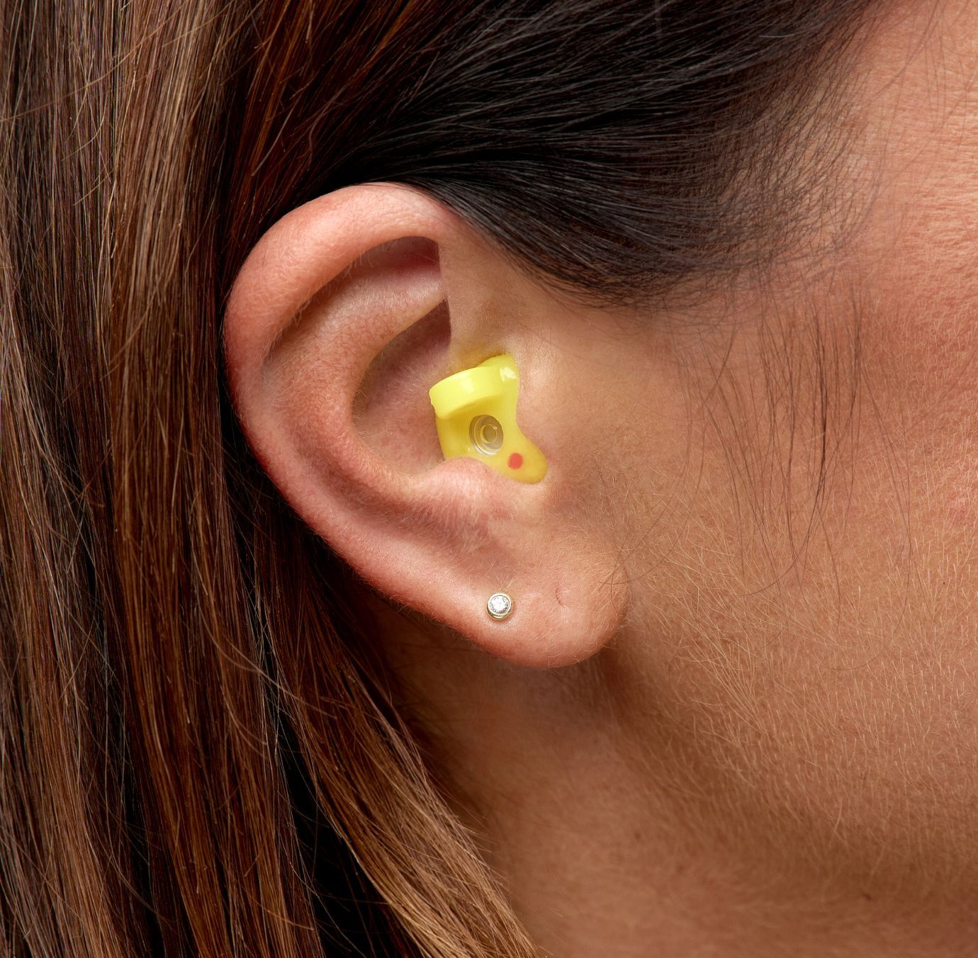 Detaljni prikaz Earwear zaštite za sluh žute boje u uhu žene