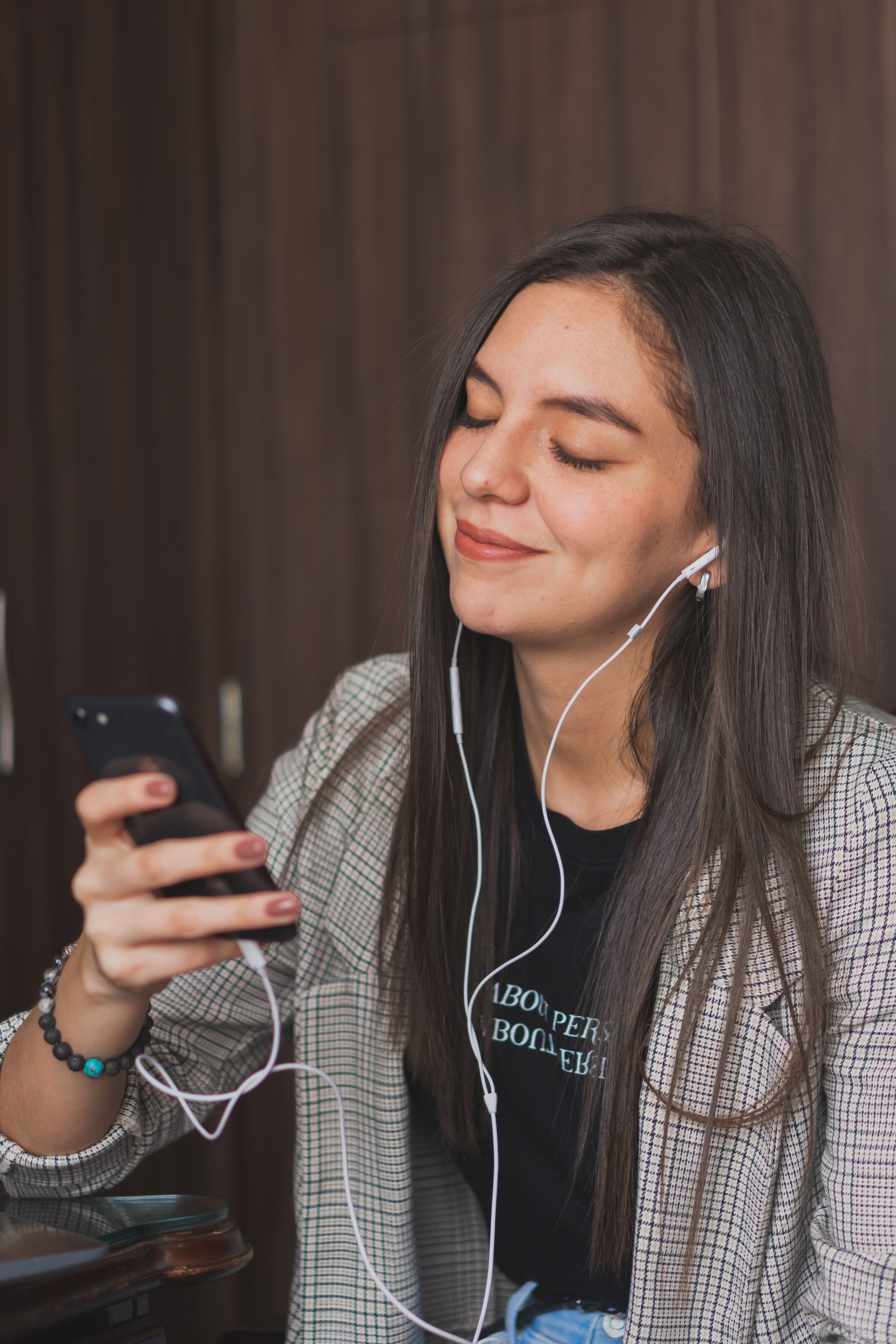Djevojka sa slušalicama u ušima povezanim na mobilni telefon uživa u muzici