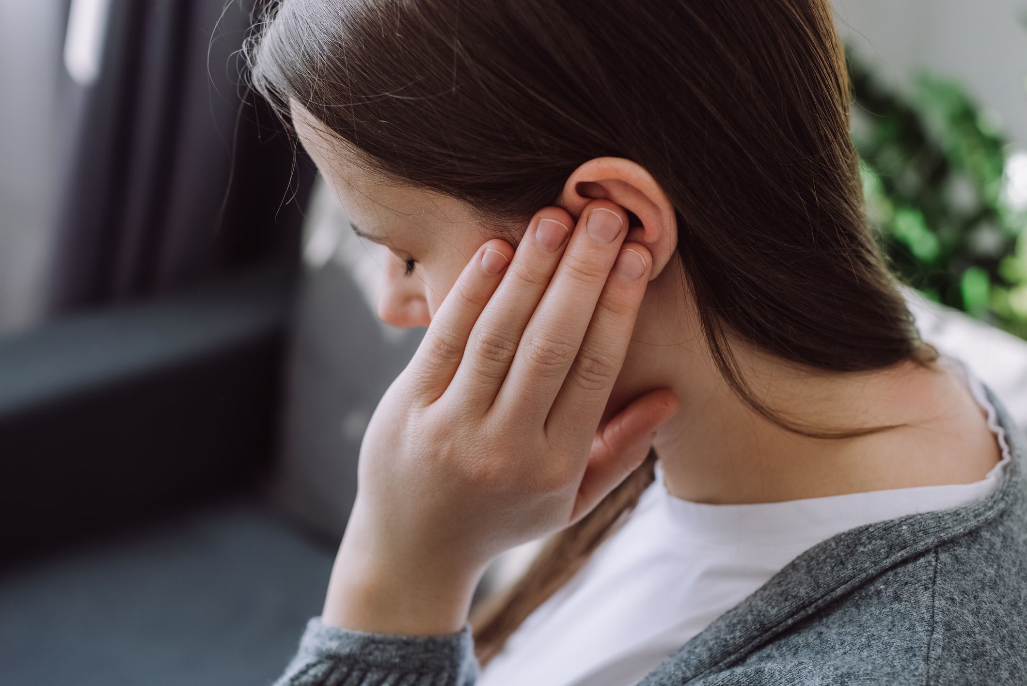 Femme porte sa main gauche à l'oreille