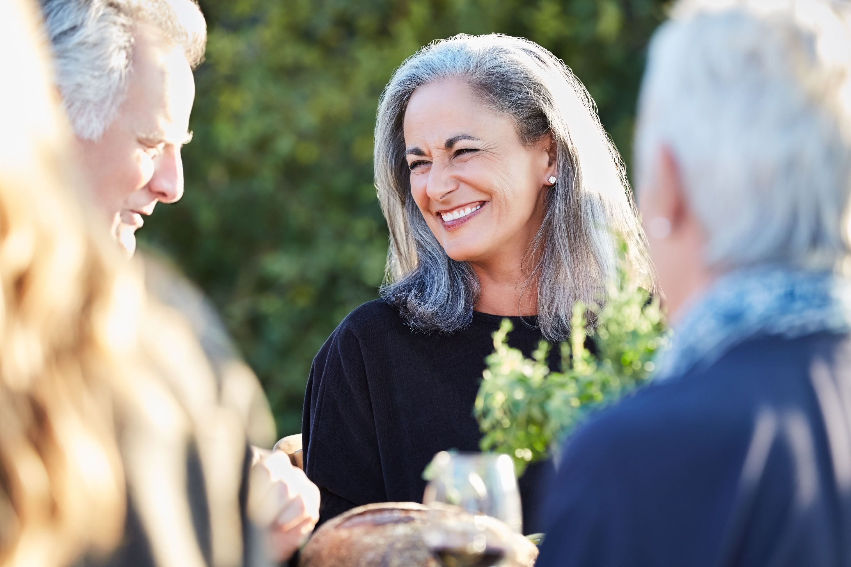 Femme souriante aux cheveux gris mi longs dans un groupe