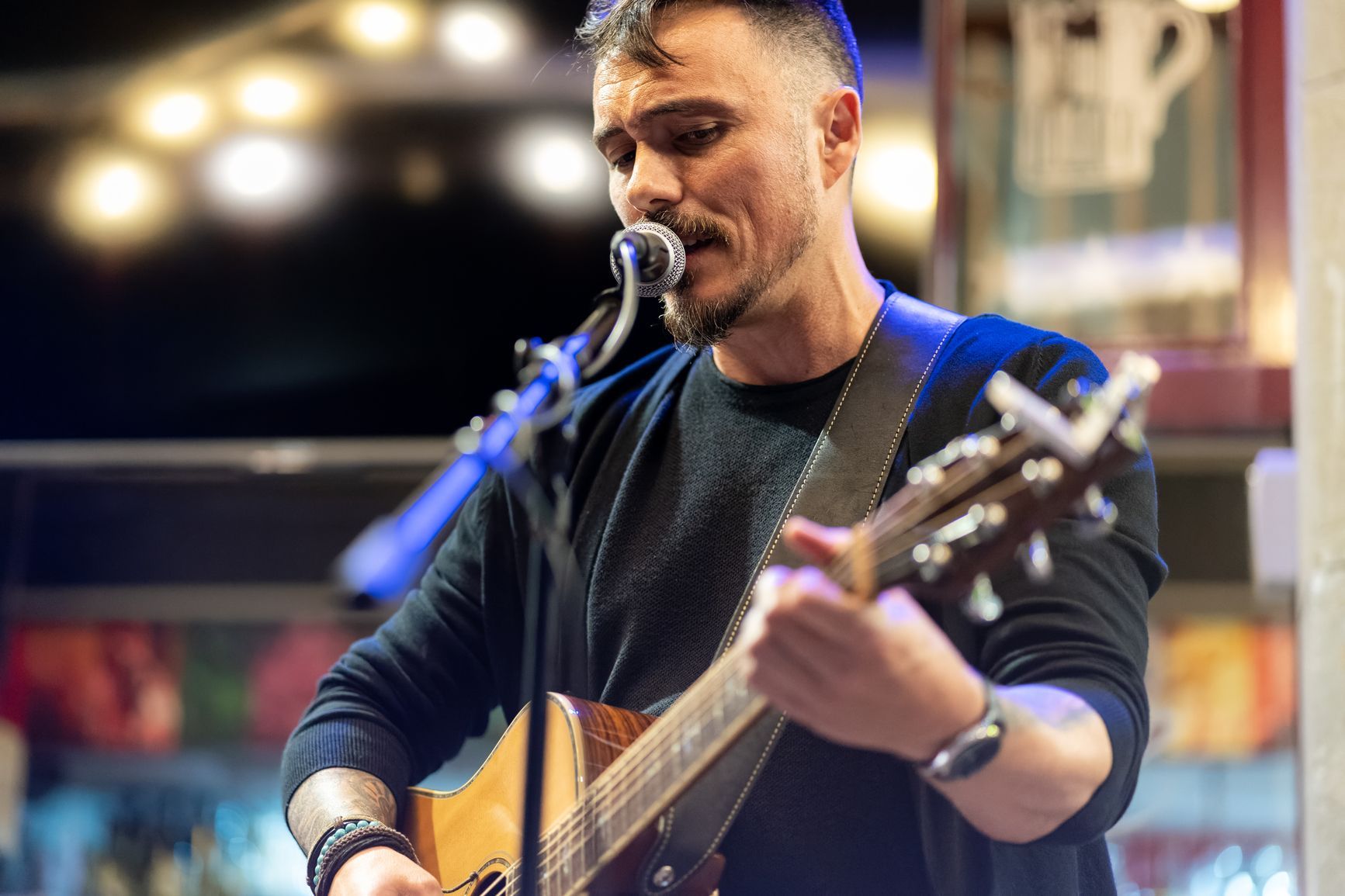 Mladi glazbenik svira akustičnu gitaru i pjeva na koncertu