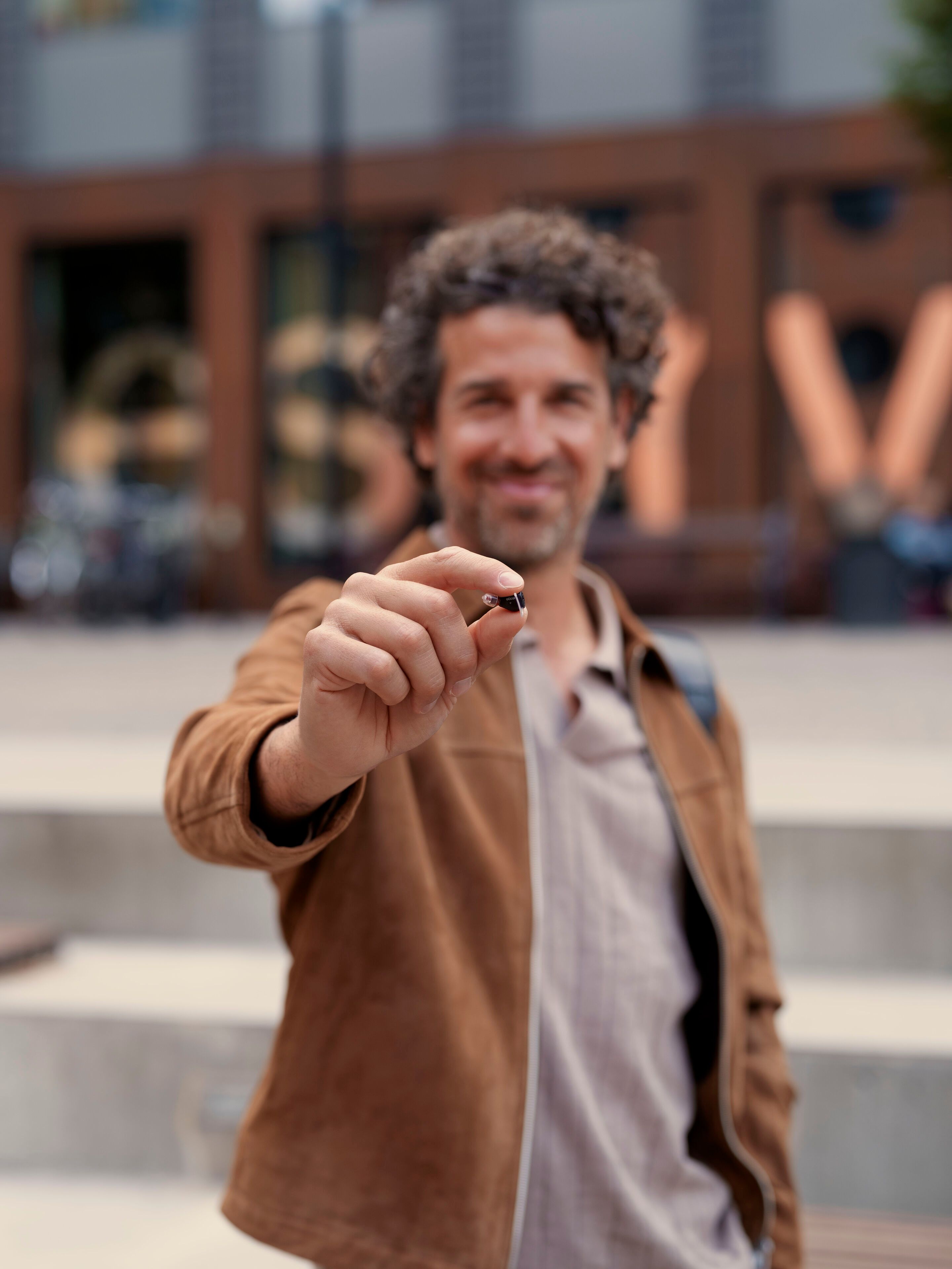 Homme avec appareil auditif Oticon Zeal dans la main