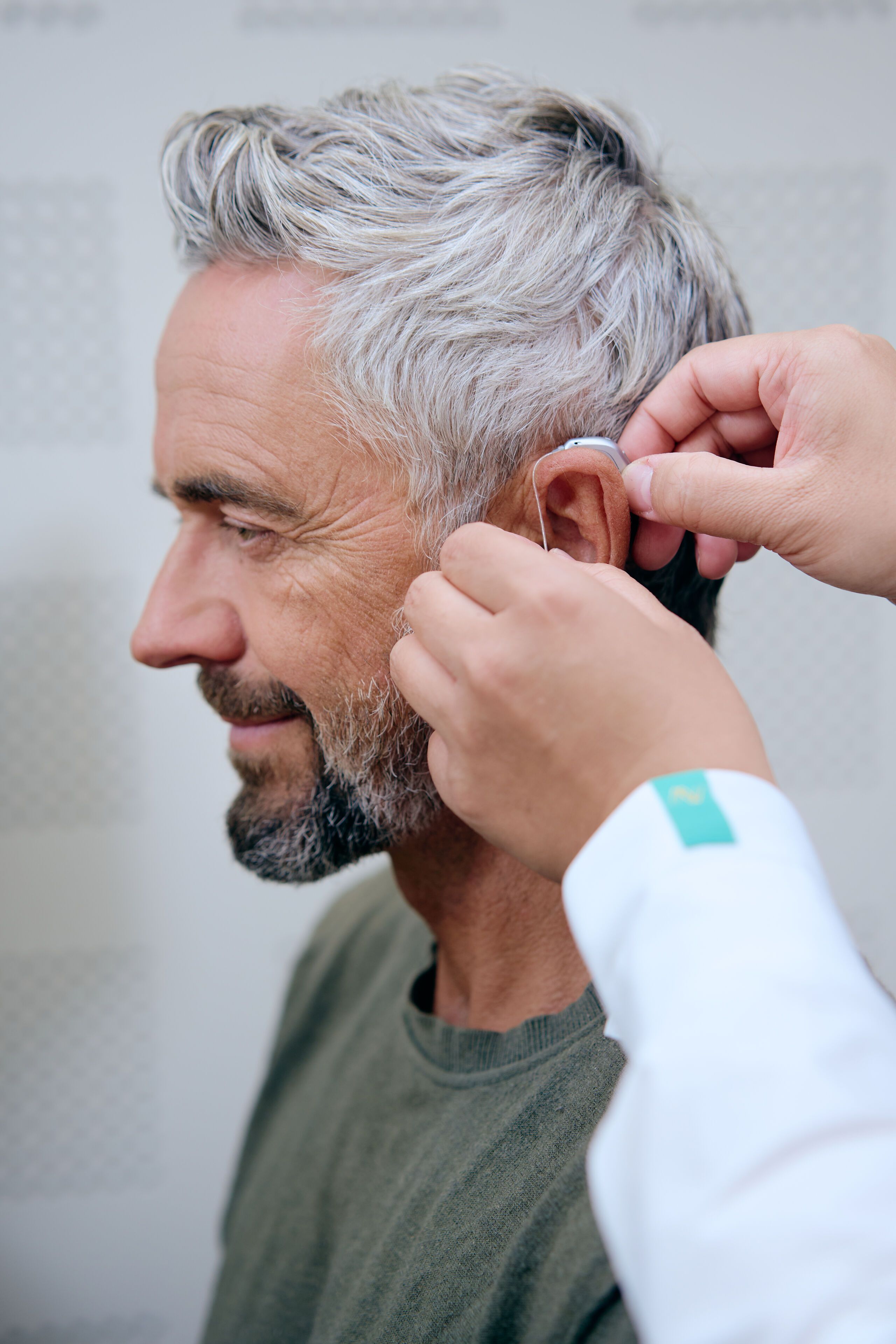 Homme se fait ajuster un appareil auditif derriere l oreille