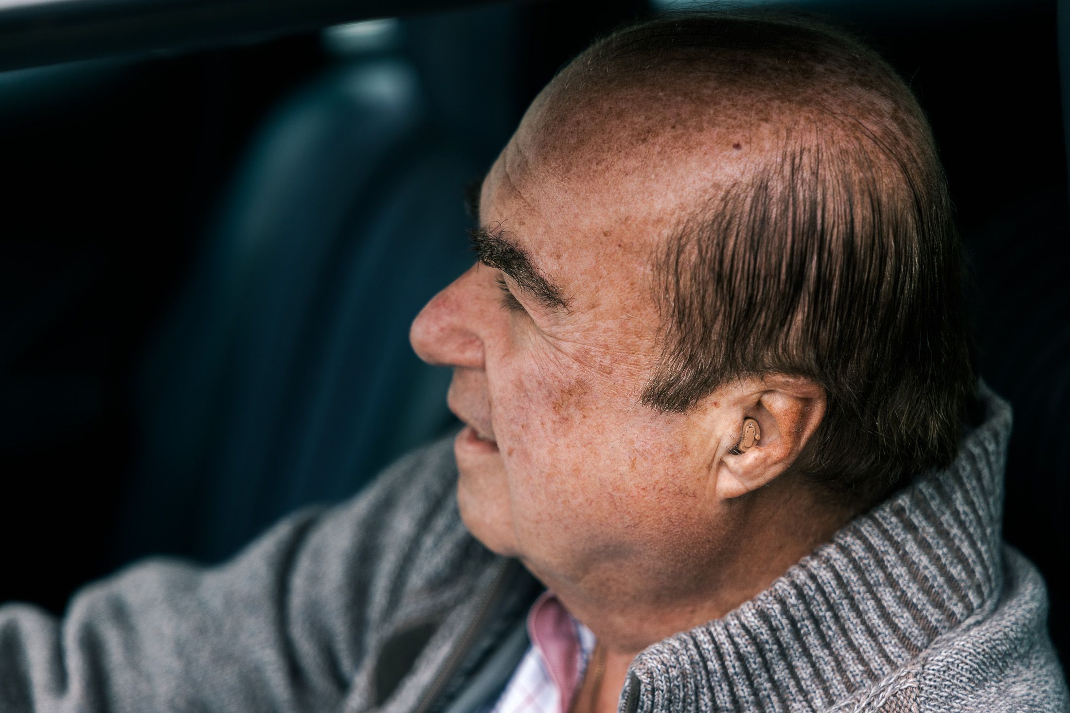 Johannes Besau in grauem Pulli, sitzt in seinem Auto. Man sieht sein Hörgerät.