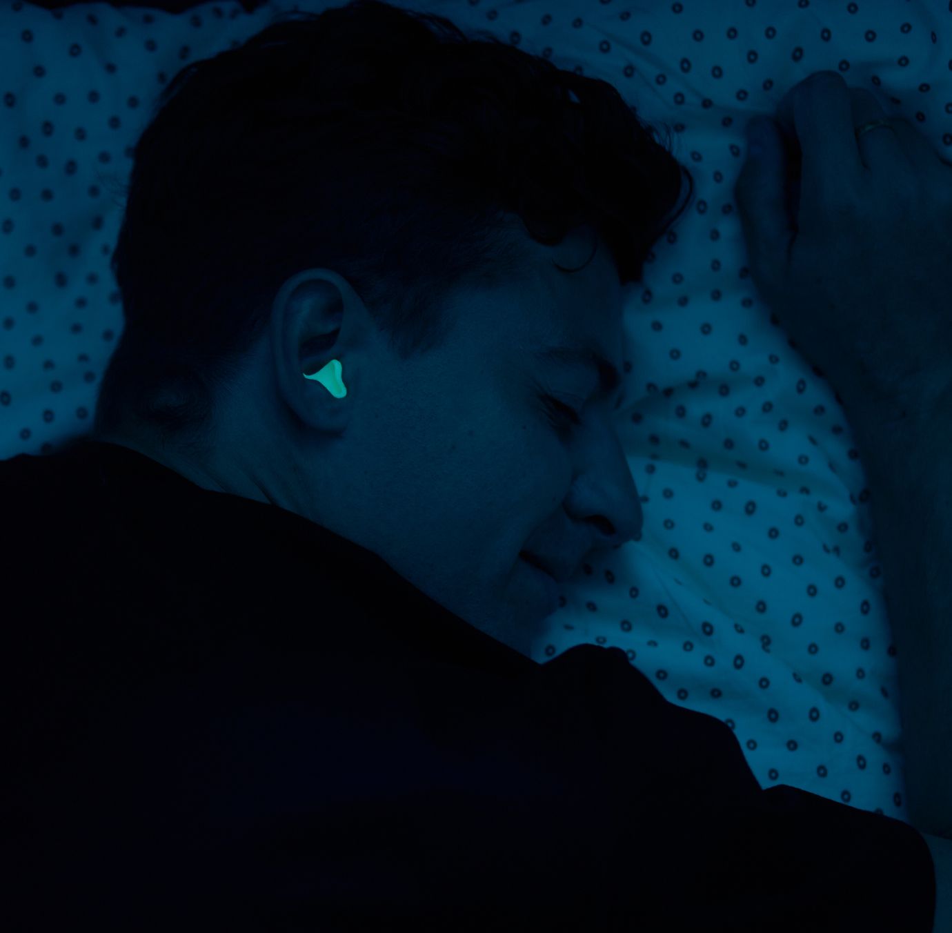 Mann beim Schlafen mit fluoreszierendem Gehörschutz