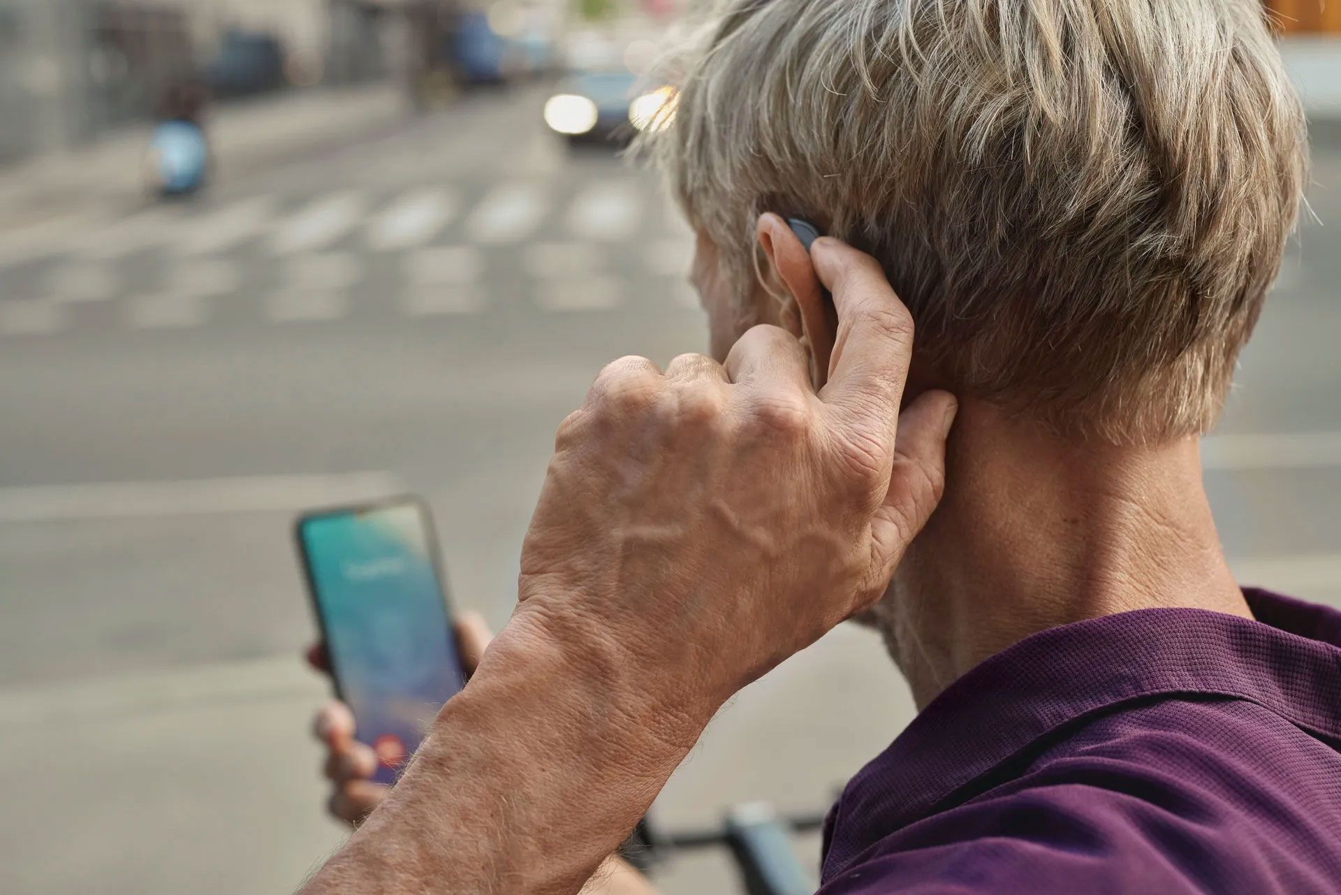 Starejši moški govori po telefonu s slušnim aparatom.
