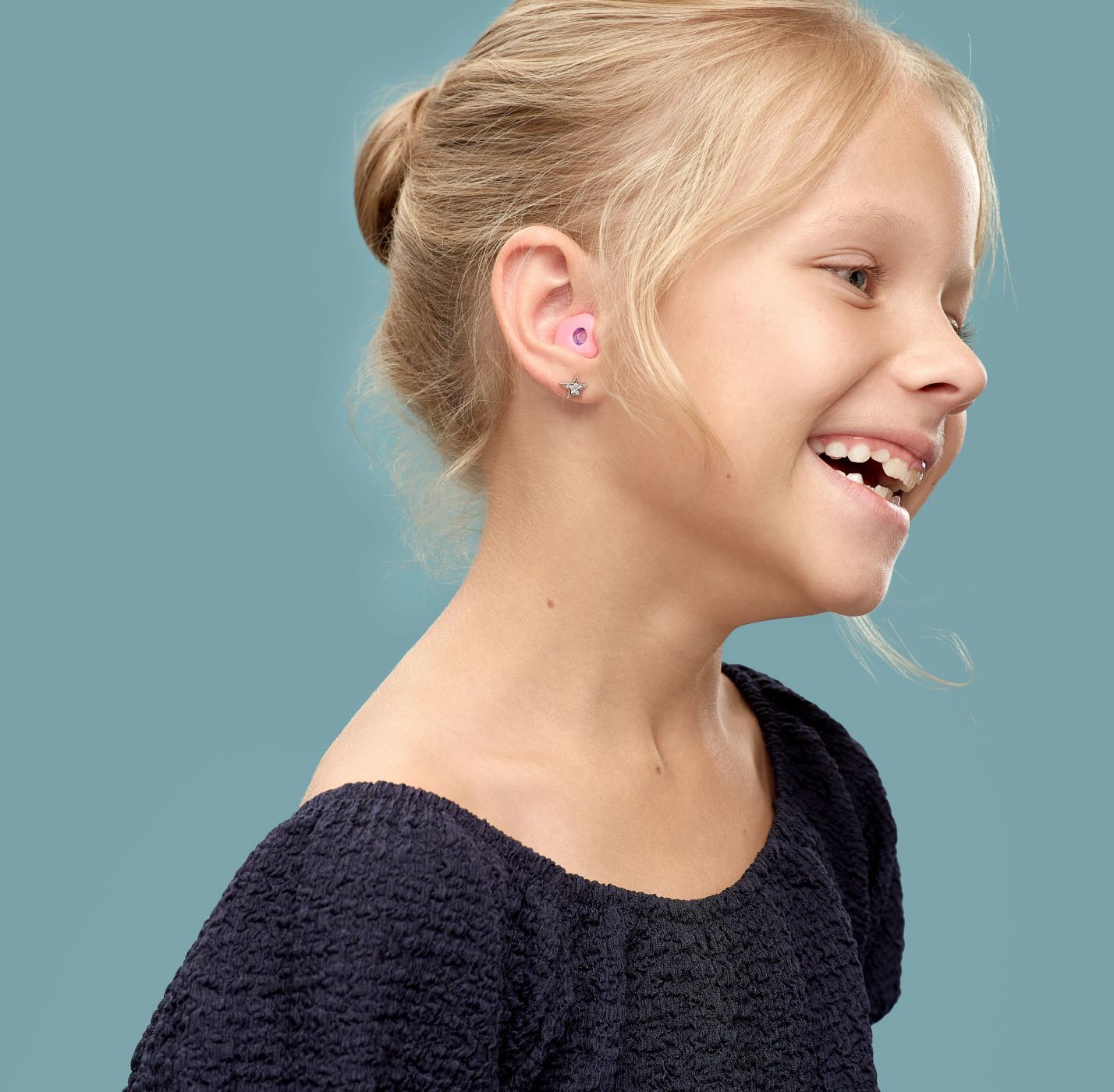 Nasmejana devojcica plave kose sa earwear sleep zastitom za usi
