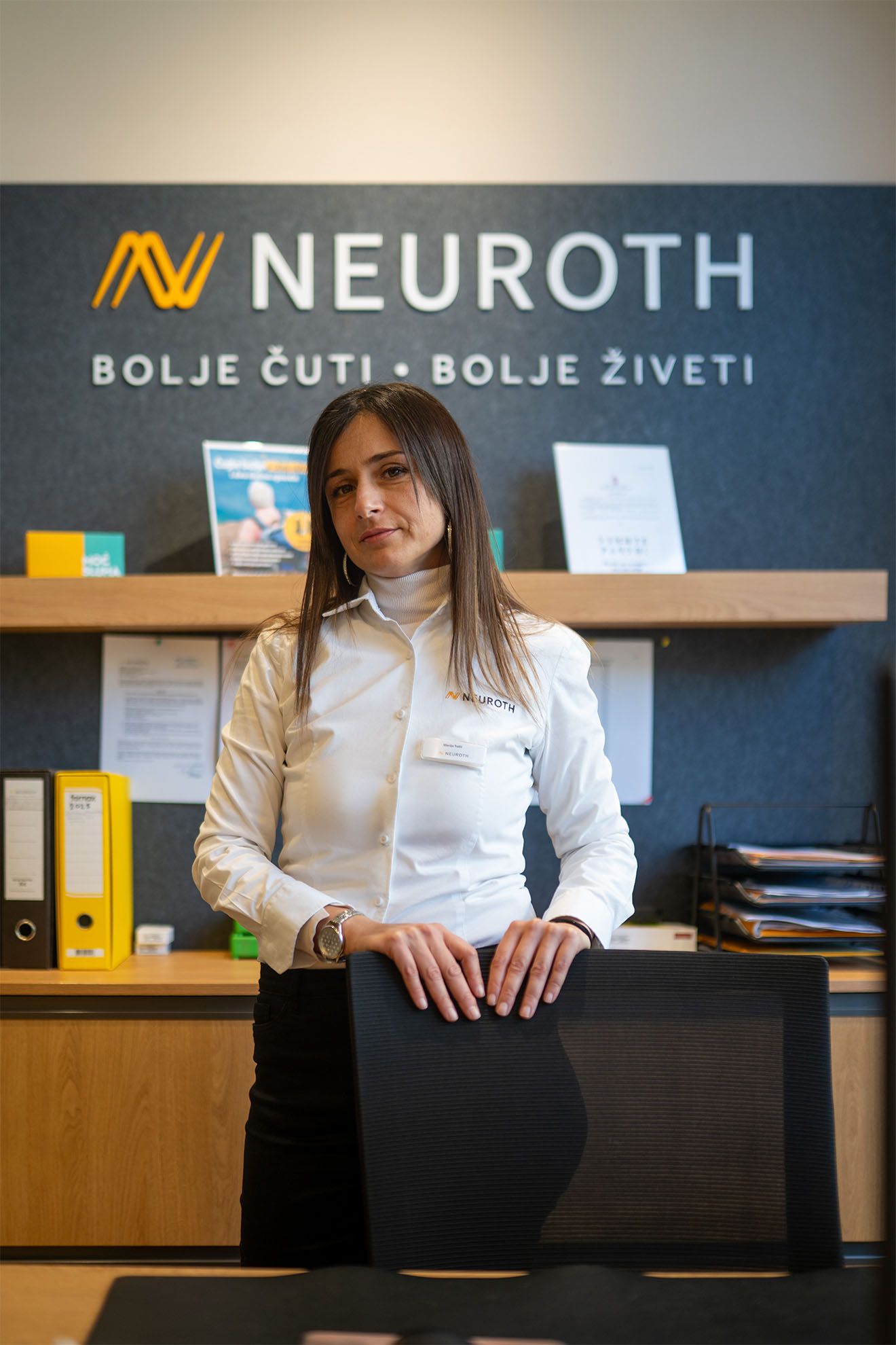 Neuroth akusticarka stoji u slusnom centru pored stolice sa Neuroth logom u pozadini