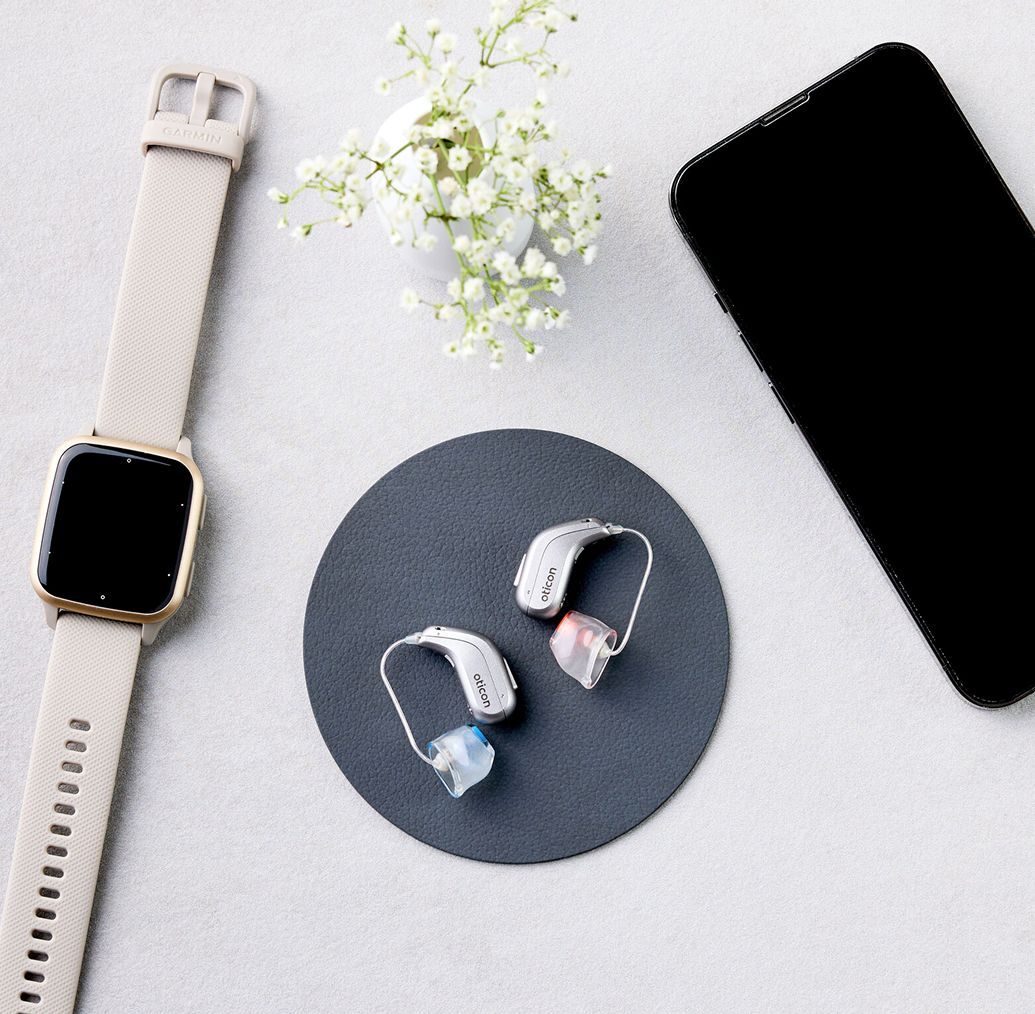 Oticon Intent Hörgeärte neben Uhr und Handy