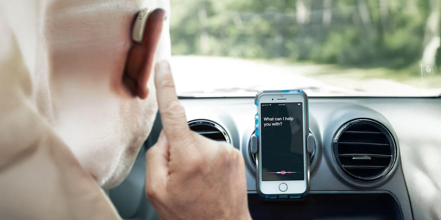 Covek koji vozi sa slusnim aparatom I povezan je sa  mobilnim telefonom 