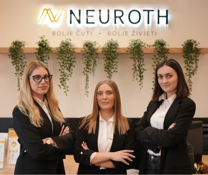 Tri mlade Neuroth akustičarke stoje skrštenih ruku u prostorijama Neurotha, sa logom kompanije iznad njih