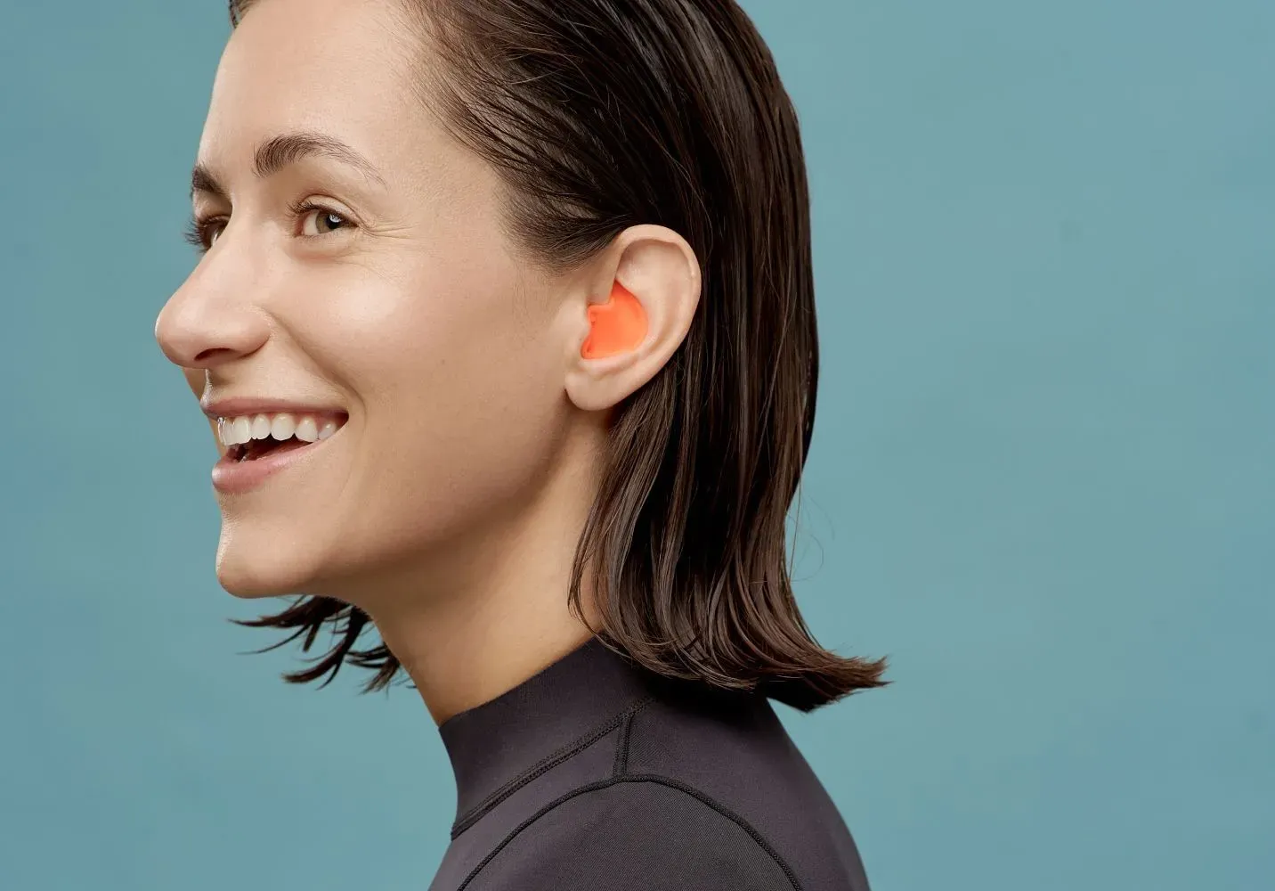 Zena mokre kose u plivackom odelu sa Earwear Swim zastitom narandzaste boje u uhu 