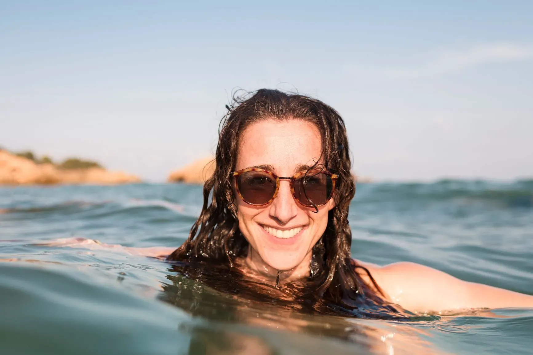 Nasmijana žena sa naočarima za sunce u vodi na otvorenom